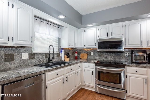 kitchen featuring a sink, wood finished floors, white cabinetry, tile countertops, and appliances with stainless steel finishes