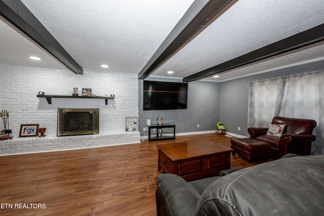 living room featuring a brick fireplace, baseboards, beam ceiling, wood finished floors, and a textured ceiling