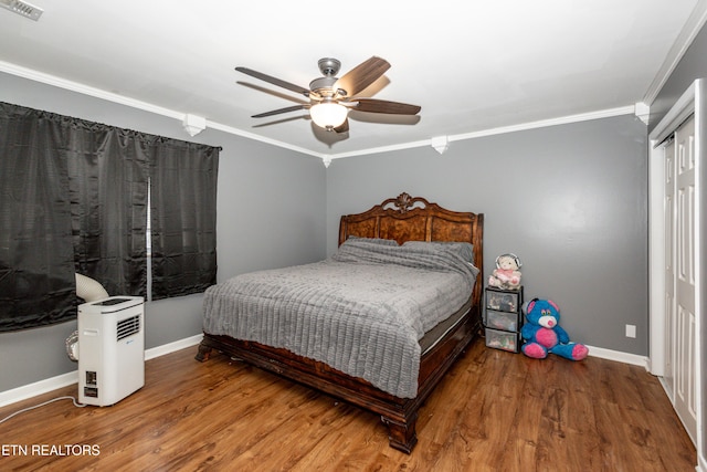 bedroom with visible vents, wood finished floors, baseboards, and ornamental molding