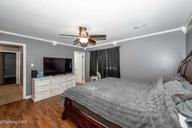 bedroom with a ceiling fan, wood finished floors, visible vents, baseboards, and crown molding