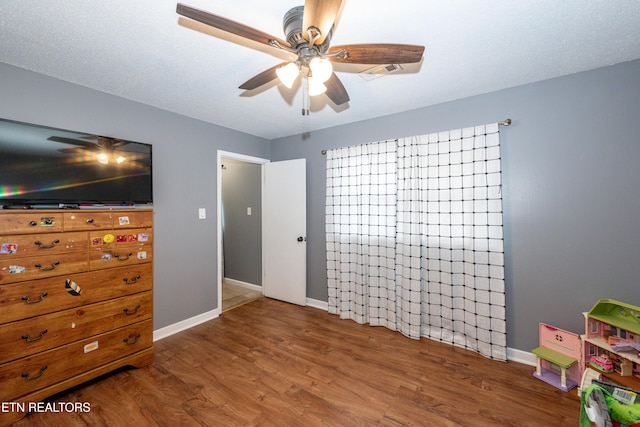 bedroom featuring ceiling fan, baseboards, and wood finished floors