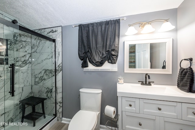 full bathroom featuring a shower stall, baseboards, toilet, vanity, and a textured ceiling