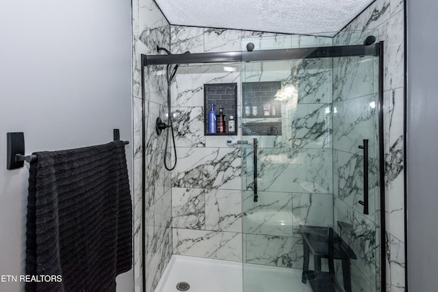 bathroom with a marble finish shower and a textured ceiling