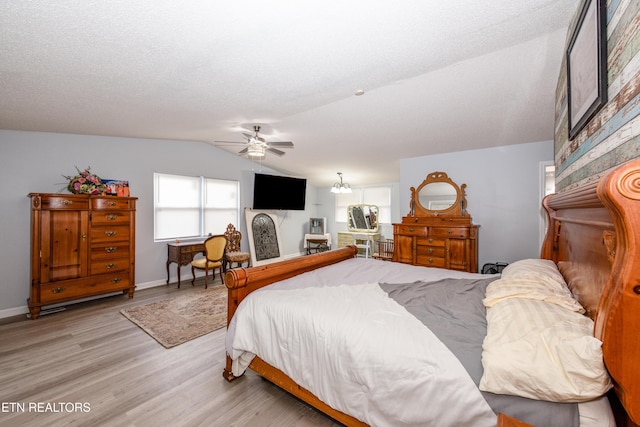 bedroom featuring vaulted ceiling, baseboards, light wood finished floors, and a textured ceiling