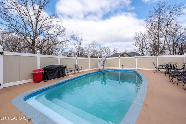 view of swimming pool with a fenced in pool, a water slide, a fenced backyard, and a patio area