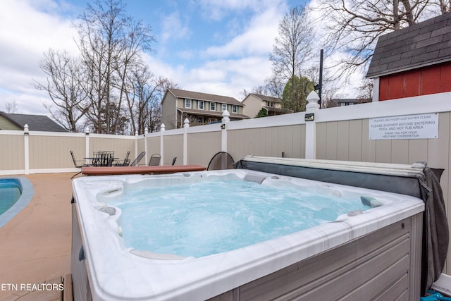 view of swimming pool featuring a hot tub and fence