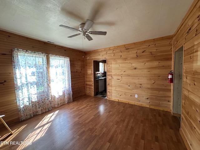 921 Winchester Ave, Middlesboro, KY 40965 - empty room with wood finished floors, a ceiling fan, visible vents, and wood walls