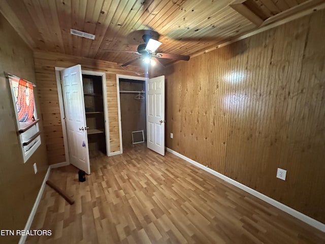 921 Winchester Ave, Middlesboro, KY 40965 - unfurnished bedroom featuring wood finished floors, visible vents, wood walls, wooden ceiling, and two closets