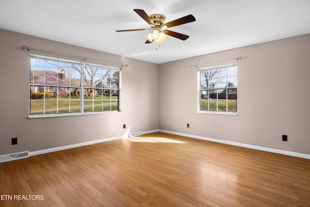 unfurnished room featuring visible vents, a healthy amount of sunlight, light wood-type flooring, and baseboards