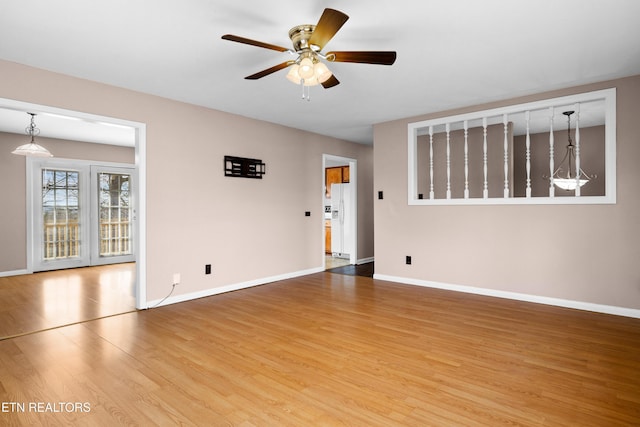 empty room featuring baseboards, wood finished floors, and a ceiling fan