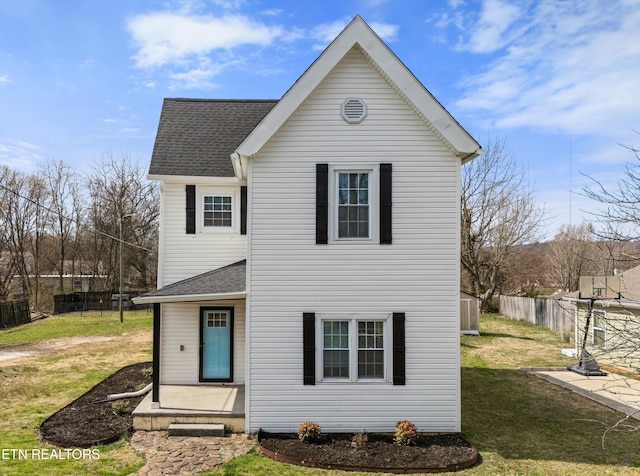 traditional home featuring a front yard, fence, and a shingled roof