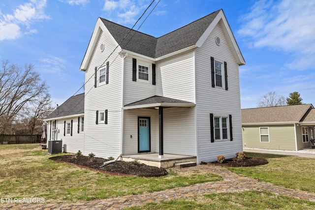 view of front facade featuring a front yard, cooling unit, and a shingled roof