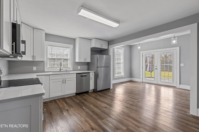 kitchen featuring a sink, stainless steel appliances, french doors, light countertops, and dark wood-style flooring