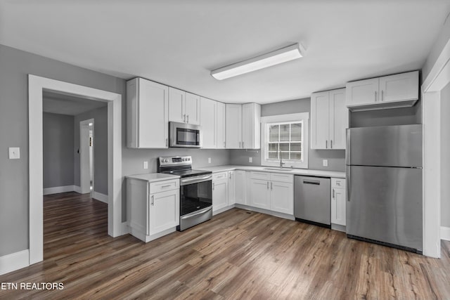 kitchen with light countertops, white cabinets, wood finished floors, and stainless steel appliances