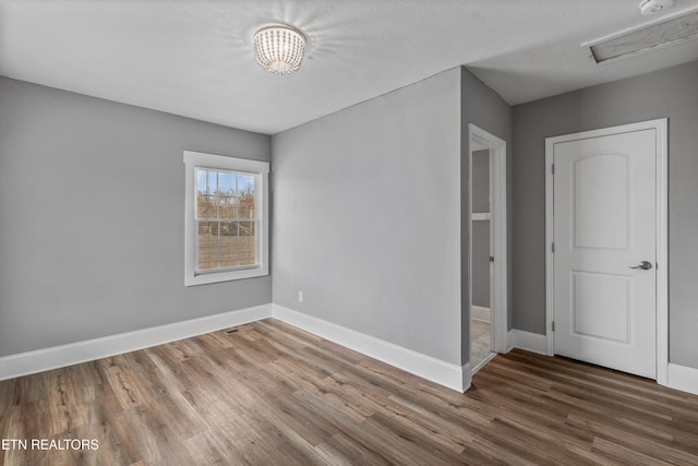 unfurnished room with baseboards, a textured ceiling, and wood finished floors