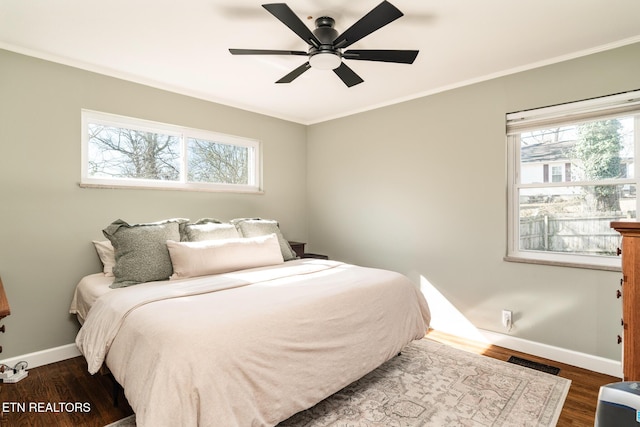 bedroom with visible vents, dark wood-type flooring, crown molding, baseboards, and ceiling fan