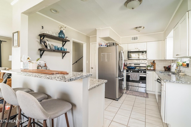 kitchen featuring visible vents, ornamental molding, a sink, light stone counters, and stainless steel appliances