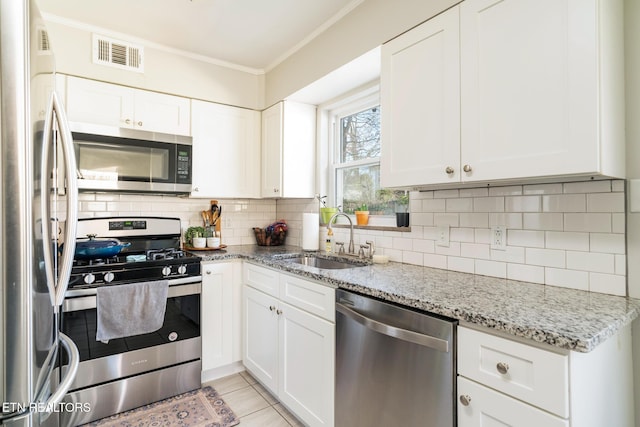 kitchen with visible vents, a sink, tasteful backsplash, appliances with stainless steel finishes, and crown molding