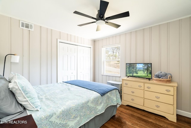 bedroom with dark wood finished floors, a ceiling fan, visible vents, and a closet