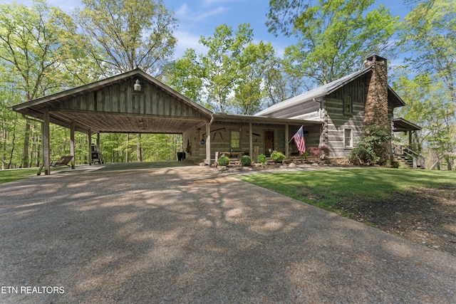 view of front of house featuring a front yard, a chimney, aphalt driveway, and an attached carport