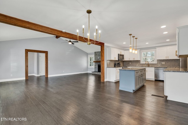 kitchen featuring lofted ceiling with beams, open floor plan, appliances with stainless steel finishes, tasteful backsplash, and a center island