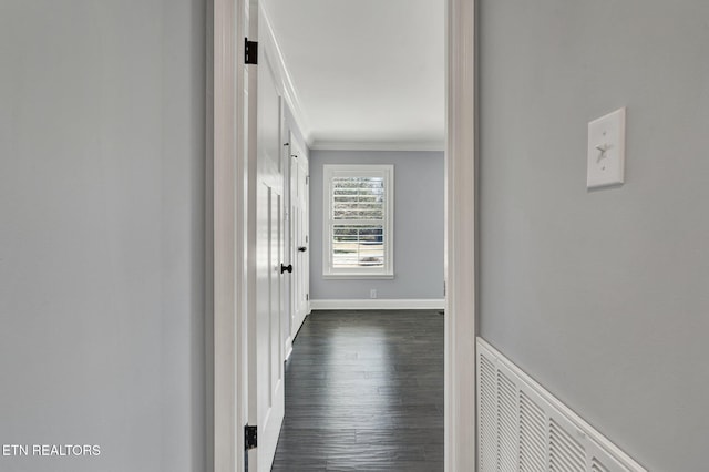 hallway with visible vents, baseboards, ornamental molding, and dark wood-style flooring