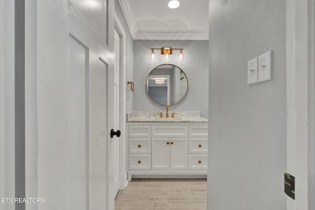 bathroom with vanity, wood finished floors, and ornamental molding