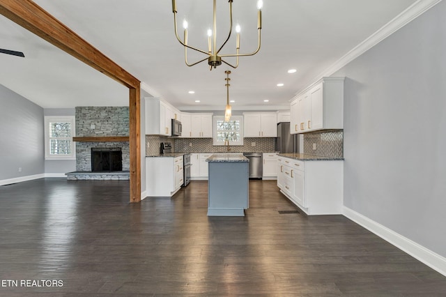 kitchen featuring a kitchen island, open floor plan, decorative backsplash, appliances with stainless steel finishes, and a notable chandelier