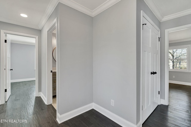 hallway featuring dark wood-type flooring, crown molding, and baseboards