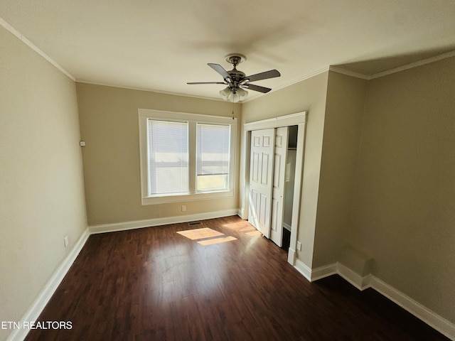 unfurnished bedroom featuring crown molding, wood finished floors, baseboards, and a closet