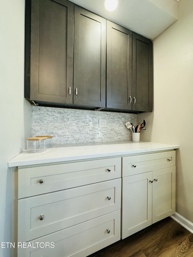 interior space featuring light countertops, dark wood-style floors, tasteful backsplash, and baseboards