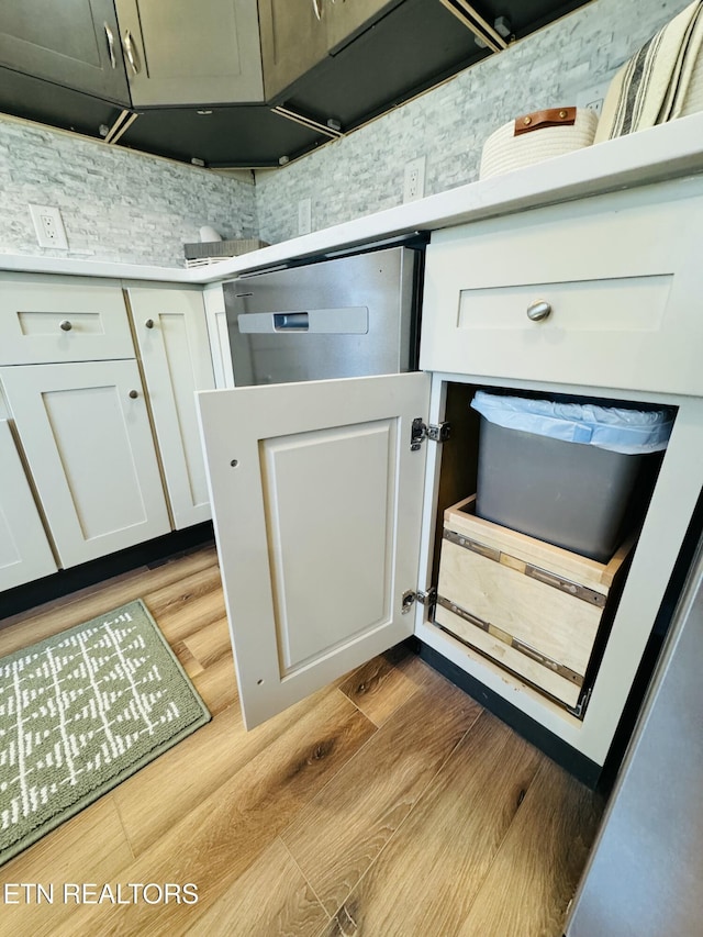 room details with decorative backsplash, light wood-style floors, white cabinets, and light countertops