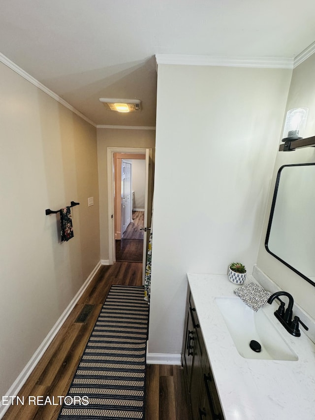 bathroom featuring vanity, crown molding, baseboards, and wood finished floors