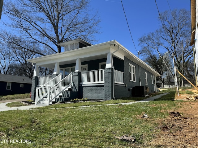 view of front of home featuring brick siding, covered porch, a front lawn, and central AC