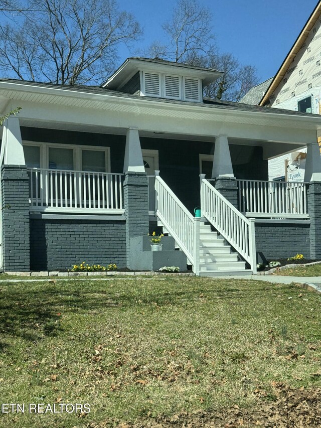 view of front of property with brick siding, covered porch, and a front yard