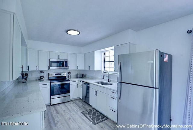 2218 Red Bank Cir, Sevierville, TN 37862 - kitchen featuring light stone countertops, a sink, white cabinets, light wood-style floors, and appliances with stainless steel finishes