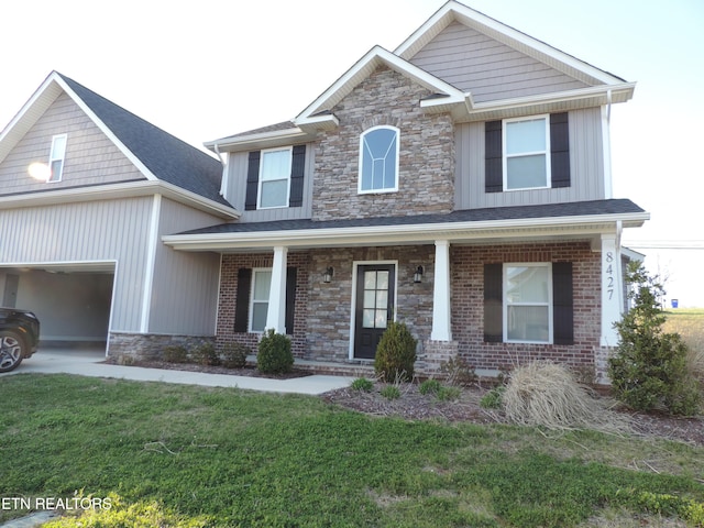 craftsman-style home with a porch, a garage, a front yard, and stone siding