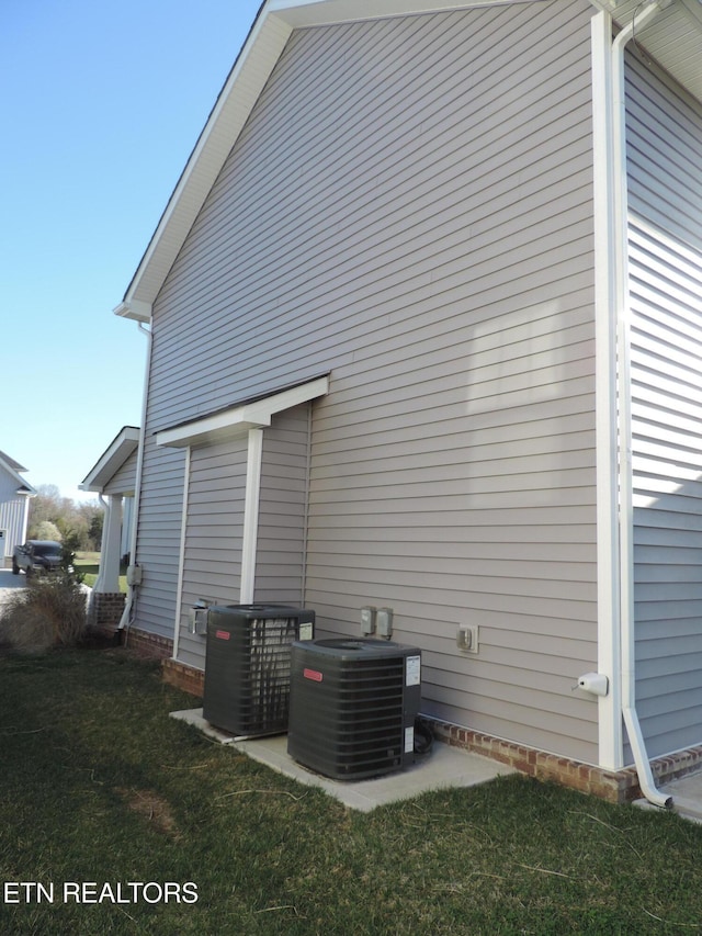 back of property with central AC unit and a lawn