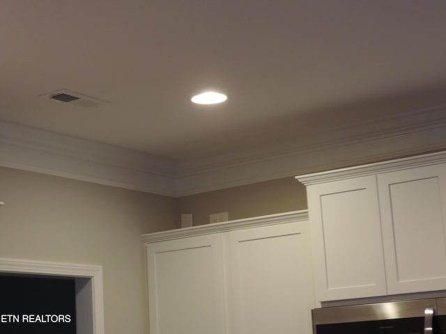 details with crown molding, visible vents, and white cabinets