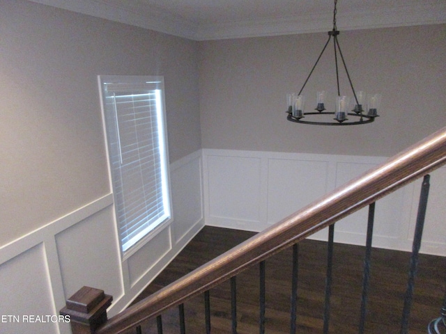 stairs featuring a decorative wall, a notable chandelier, and wainscoting
