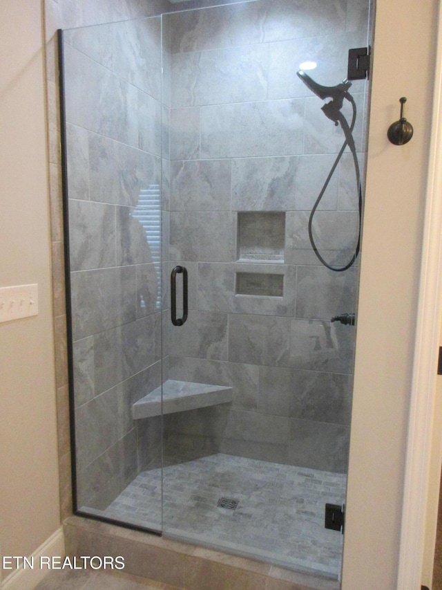 full bath featuring a shower stall and baseboards