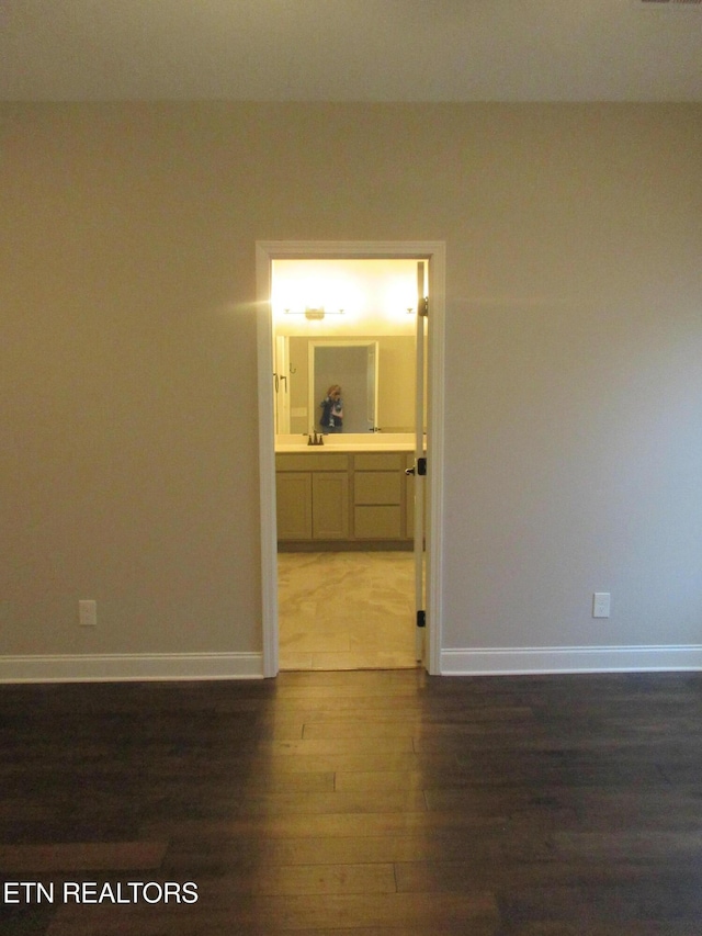 empty room featuring baseboards and dark wood finished floors