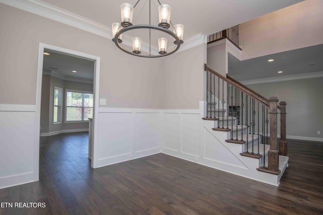 interior space featuring a notable chandelier, crown molding, wainscoting, a decorative wall, and wood finished floors