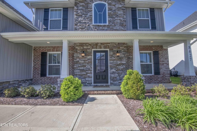 property entrance featuring a porch, stone siding, and board and batten siding