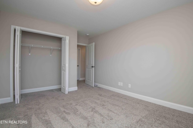 unfurnished bedroom with a closet, baseboards, and carpet