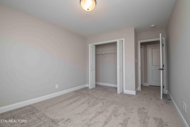unfurnished bedroom featuring a closet, baseboards, and carpet