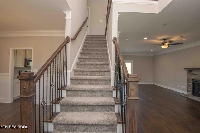 staircase featuring a ceiling fan, a fireplace, crown molding, recessed lighting, and wood finished floors