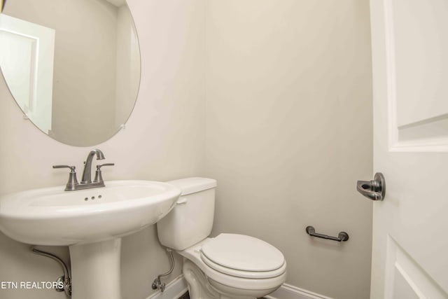 half bathroom with baseboards and toilet