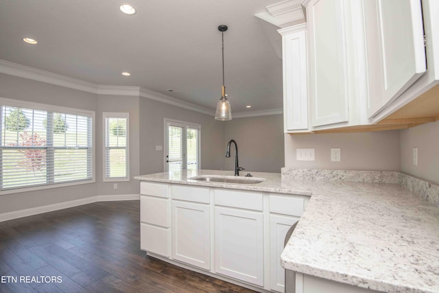 kitchen featuring a sink, ornamental molding, white cabinets, and a peninsula