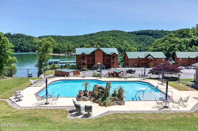 pool featuring a patio area, fence, and a forest view